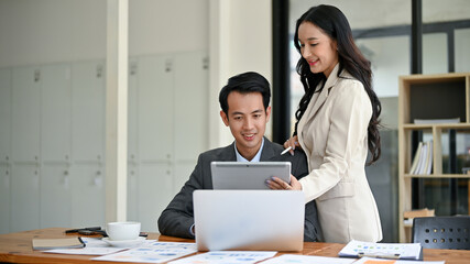 Fototapeta na wymiar A beautiful millennial Asian businesswoman is briefing a male employee