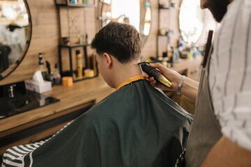 Back view of man sitting on chair in barbershop. 