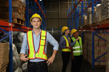 Group of warehouse workers with hardhats and reflective jackets using tablet, walkie talkie radio...