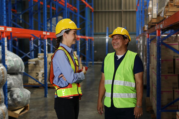 Group of warehouse workers with hardhats and reflective jackets using tablet, walkie talkie radio and cardboard while controlling stock and inventory in retail warehouse logistics, distribution center