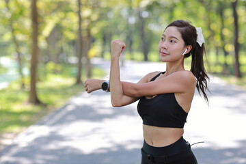 Portrait of happy young asian sportswoman practice yoga stretching and meditation exercise after finish morning run outdoor. Beautiful athlete smile woman listening music under the tree in the park