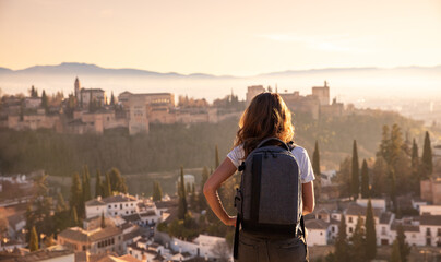 Rear view of woman enjoying sunset over Granada city landscape- Spain - obrazy, fototapety, plakaty
