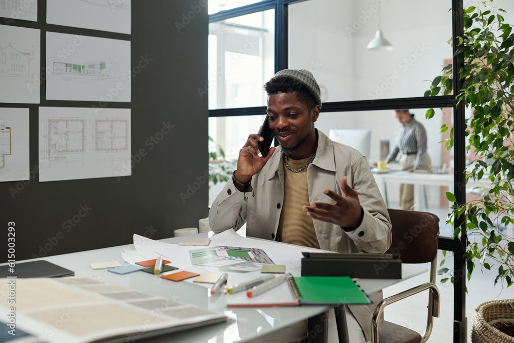 Aufkleber young successful architect with smartphone by ear taking phone consultation of colleague while sitti