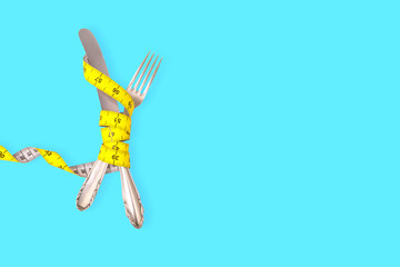 diet, weight loss and slimming, silver cutlery, fork and knife, wrapped with yellow measure tape