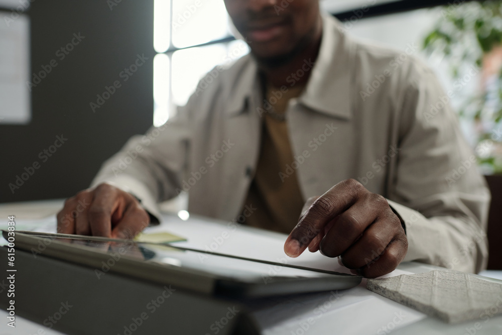 Aufkleber Focus on hand of young African American employee pointing at tablet screen while making presentation of scrolling through online data