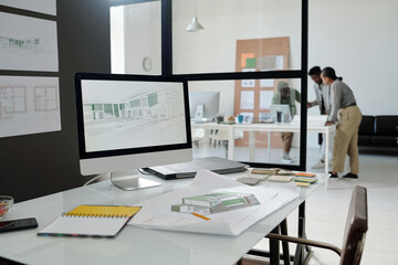Workplace of modern architect or designer with computer monitor, blueprint with sketch of building, open notebook and other supplies