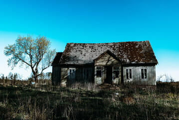 Fototapeta na wymiar Abandoned 19th century house in a rural field at summer.Creepy summer dark evening.Toned.