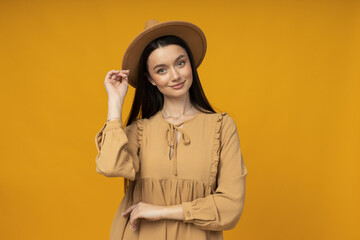 Young woman in a hat on a yellow background