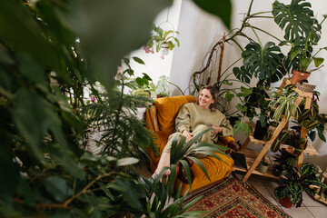 woman is resting in a home greenhouse sitting in a cozy armchair