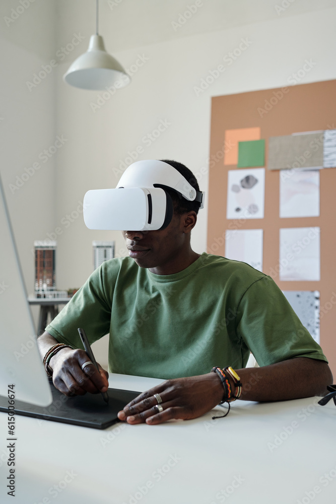 Aufkleber Young black man in green t-shirt creating new computer games or website while sitting in front of computer and using touchpad and stylus