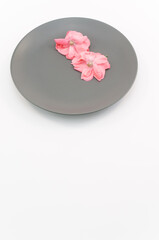 immagine primo piano con fiori di rosa selvatica di colore rosa appassiti su piatto in ceramica...