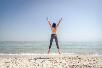 Fototapeta na wymiar Fitness Girl jumping on the beach
