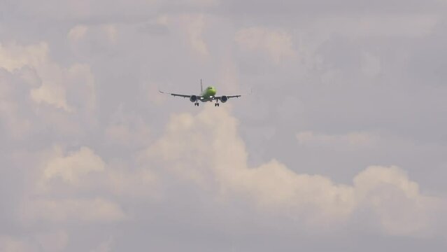 Passenger plane approaching for landing. Aircraft flies, front view. Airliner with unrecognizable green livery descending. Flight arrival