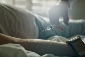 Hand of male doctor of mental hospital holding syringe with liquid medicament while making...