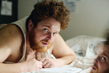Bearded young man with anxiety disorder or some other psychiatric disease looking at camera while...