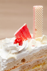 Close-up of a Delicious Pineapple pastry with a cherry and wafer on top. On a white plate. Front view.