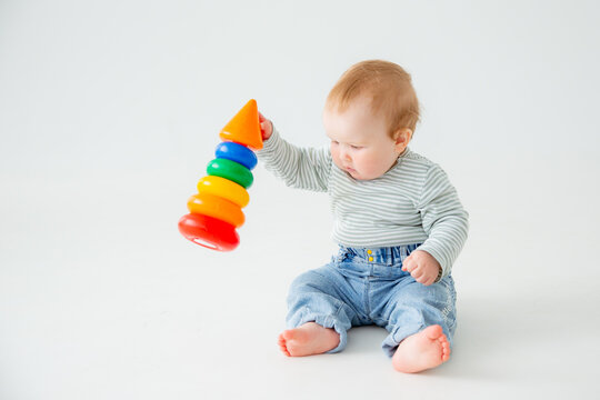 charming baby in a T-shirt and jeans is playing with toys, a postcard, a banner, a place for text. High quality photo