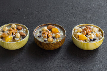 Traditional Turkish Dessert Ashure or Noah's Puding,designed in bamboo bowls on black surface