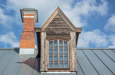 The roof of the house with an attic window and a chimney