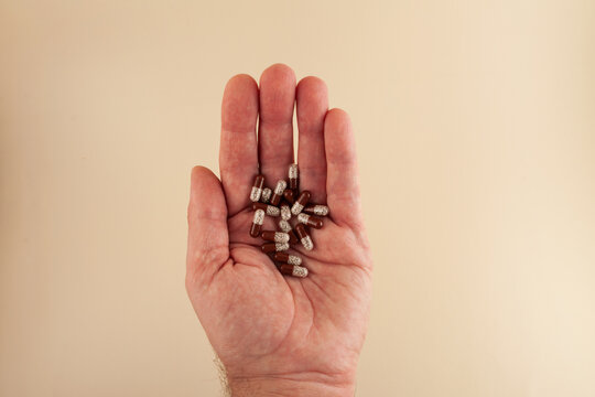 Pancreatin capsules or Creon pills on the palm elderly man, close-up. Pancreatin contains the pancreatic enzymes trypsin, amylase and lipase