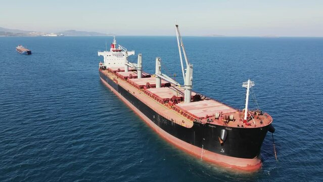 Cargo bulk vessel anchored in sea waiting entering port, aerial view