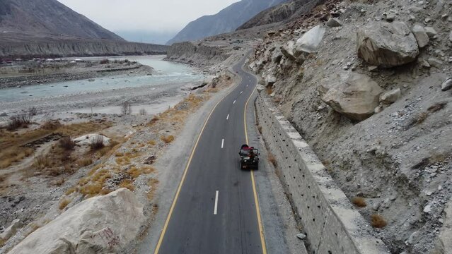 Aerial drone backward moving shot over Karakoram Highway alongside Karimabad Hunza Valley in Pakistan during evening time.