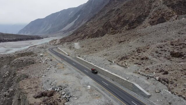 Aerial drone backward moving shot over Karakoram Highway alongside Karimabad Hunza Valley in Pakistan during evening time.