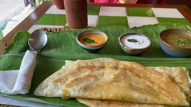 Traditional breakfast for south Indians dosa with ghee adds with butter served in coconut leaves in a theme restaurant.