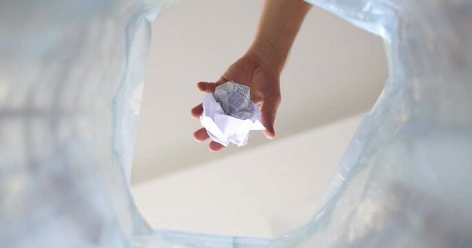 Hand throws crumpled paper into trash can. Environmental impact of paper