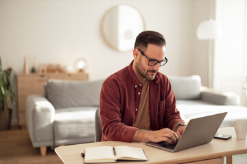 Businessman working over the laptop. typing something on it, at home.