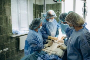 Surgical team performing surgery operation. Doctor performing surgery using sterilized equipment. Gynecologists and midwifes giving birth. Infant in maternity hospital - obrazy, fototapety, plakaty