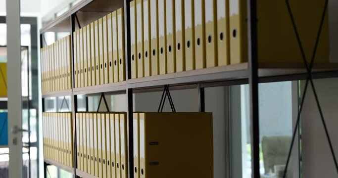 Many yellow identical folders were added to shelf in office. Archive documentation and storage of business documents