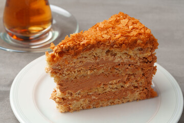 Piece of cake on plate with cup of tea on gray table