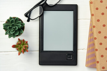 Portable e-book reader on wooden background top view