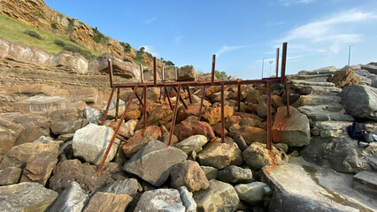 An abandoned rusty pier platform on the cliffs by the sea. Rusty steel beams, remnants of old sea...