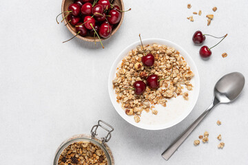 Bowl of homemade granola with nuts and cherry in white bowl on light background. Quick healthy...
