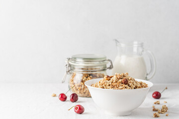 Bowl of homemade granola with nuts in white bowl on light background. Quick healthy breakfast