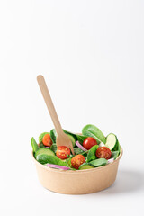 Fresh green salad in cardboard bowl on white background with copy space. Healthy food delivery concept