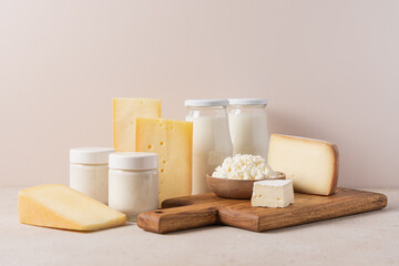 Farm dairy products on beige background. Assorted cheese, cottage cheese, milk, yogurt close-up view