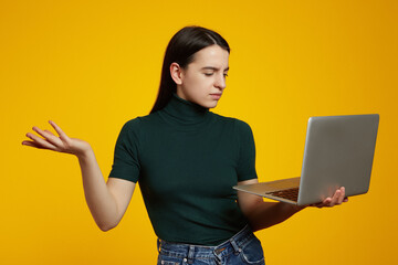 Young caucasian woman with a laptop having doubts while raising a hand, isolated over yellow...