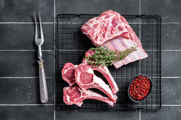 Fresh Raw lamb meat chop steaks on kitchen table with spices and herbs. Black background. Top view