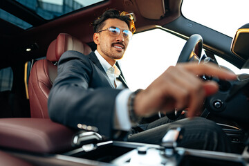 Young businessman in elegant suit driving luxury car