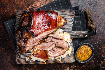 Schweinshaxe Roasted Pork Ham Hock, knuckle with Sauerkraut served on a wooden board. Dark...