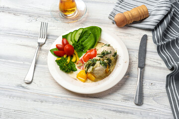 Chicken breast cooked in sauce and fresh vegetables served on plate in cafe