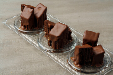 Chocolate sponge cake coated with chocolate sauce on glass plate