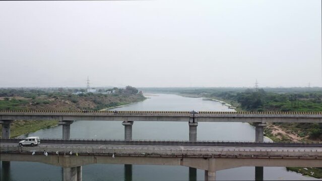 Cinematic aerial view of the highway bridge built over the river basin in the mainland Indian rural terrain, India