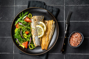 Roasted sea bass fillet with salad, Branzino fish. Black background. Top view - obrazy, fototapety, plakaty