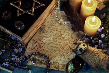 Voodoo doll with magic book of spells and candles on witch ritual table. Occult, esoteric and fortune telling still life. Mystic background with vintage objects