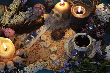 Skull candles, manuscripts with magic spells and runes on witch altar table. Occult, esoteric and fortune telling still life. Mystic background with vintage objects