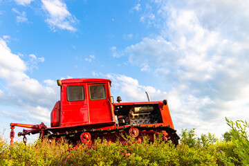 red tractor of the old model stands in the field. r